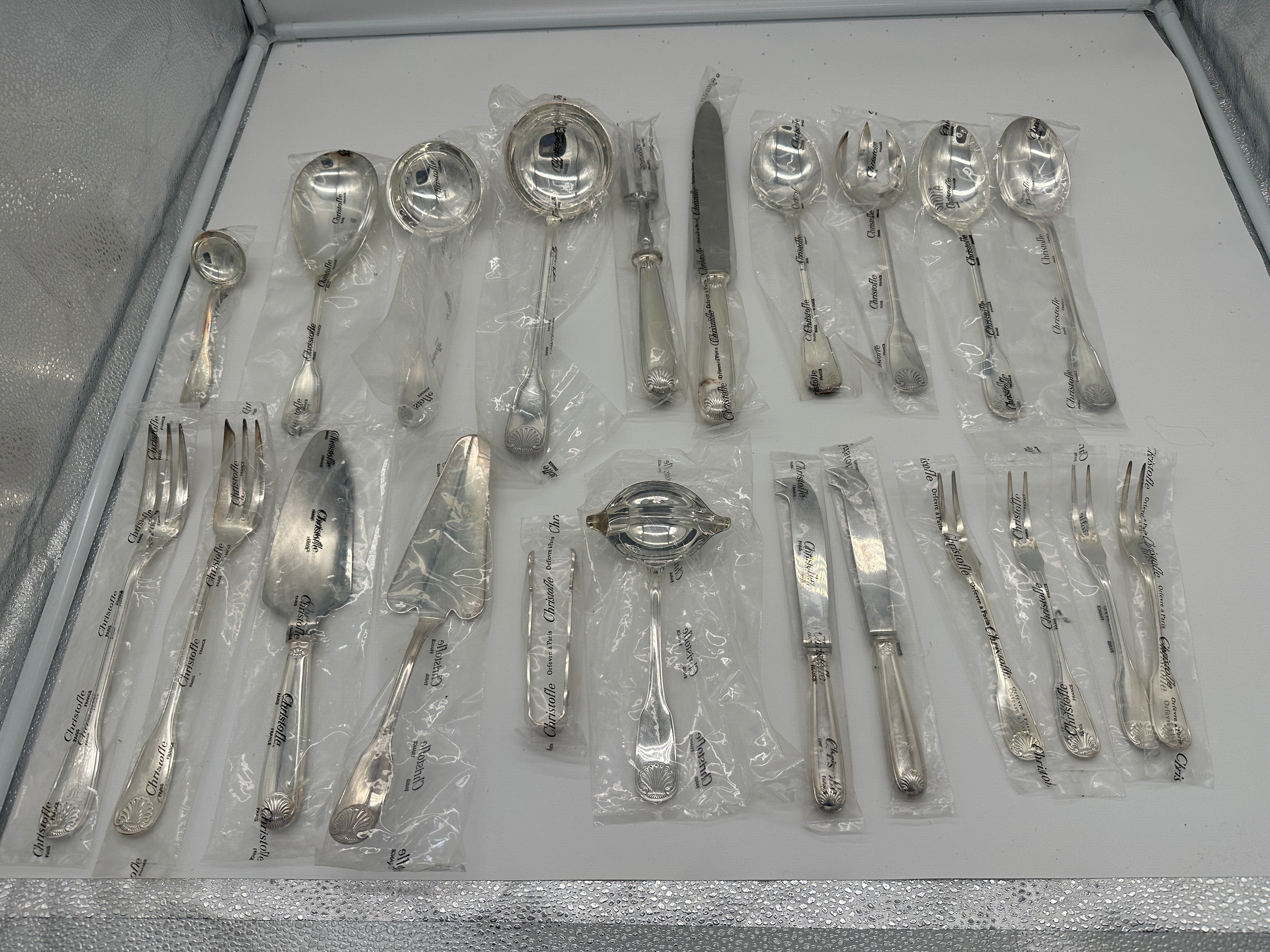 Collection of silverware set in clear plastic packaging on a gray surface.